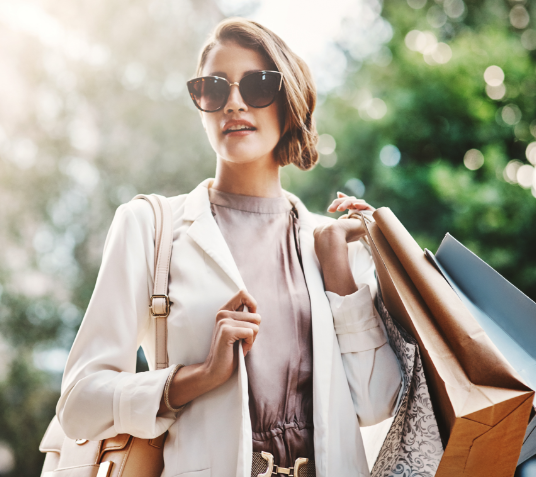 domcarre-koeln-retail-stilvolle-frau-einkaufen Stilvolle Frau mit Sonnenbrille und Einkaufstüten im Freien.